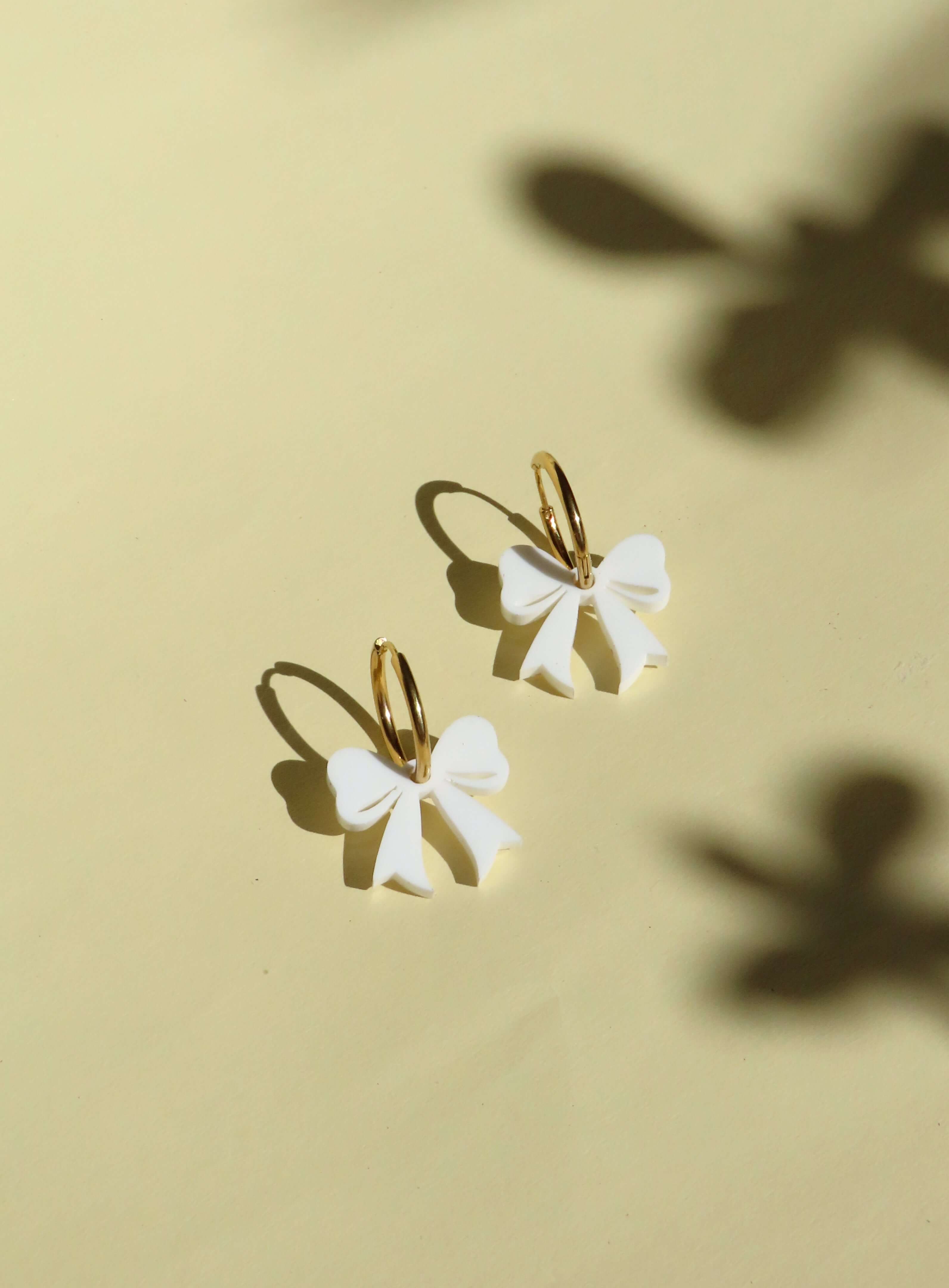 Goldene Creolen mit weißen Schleifen – verspielte Ohrringe mit 3D-Effekt